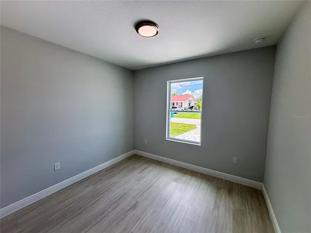 an empty room with a window and wooden floor