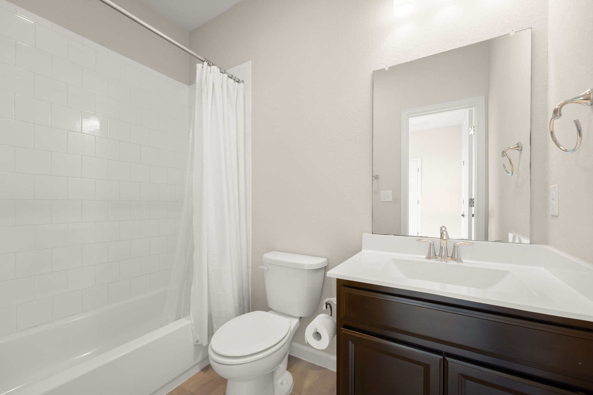 4403 Swift Path Austin, TX 78741 - Photo 20 of 32 Bathroom featuring a white subway tile shower surround, a dark wood-finish vanity with a white countertop and integrated sink, and wood-finish flooring