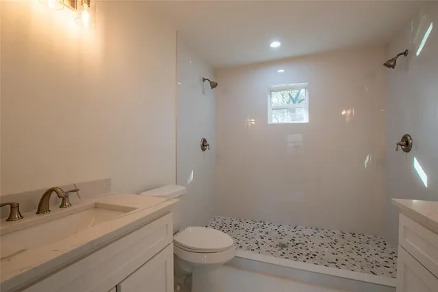 a bathroom with a granite countertop sink a toilet and a mirror