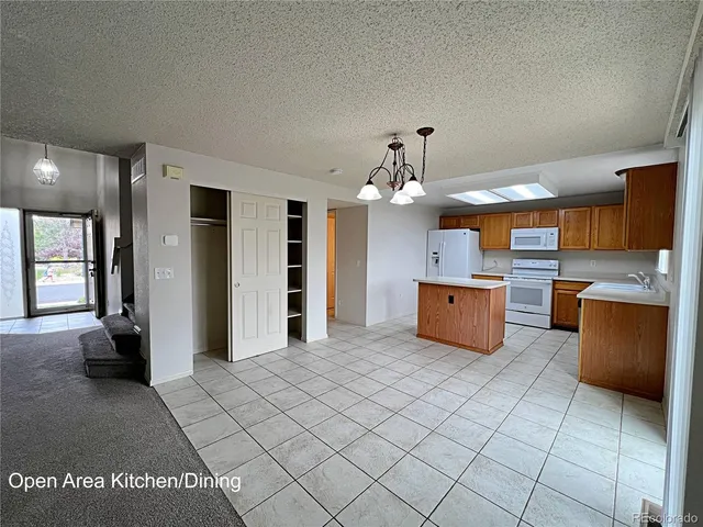 a large kitchen with stainless steel appliances kitchen island granite countertop a refrigerator and a stove top oven