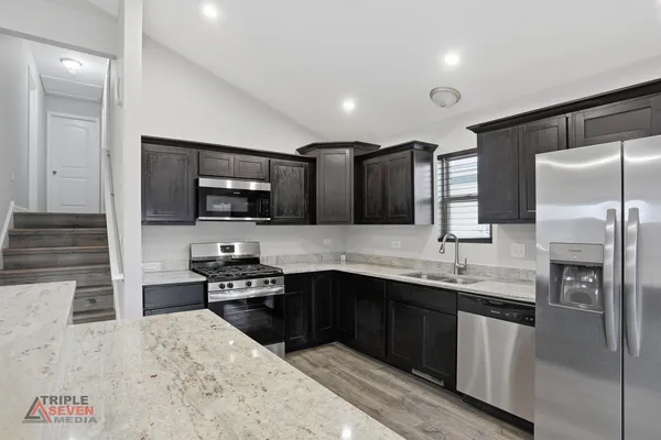 a kitchen with stainless steel appliances granite countertop a sink stove and refrigerator
