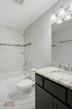 a bathroom with a granite countertop sink a toilet and shower