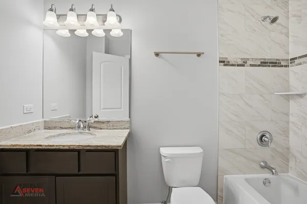 a bathroom with a sink vanity granite toilet and a mirror