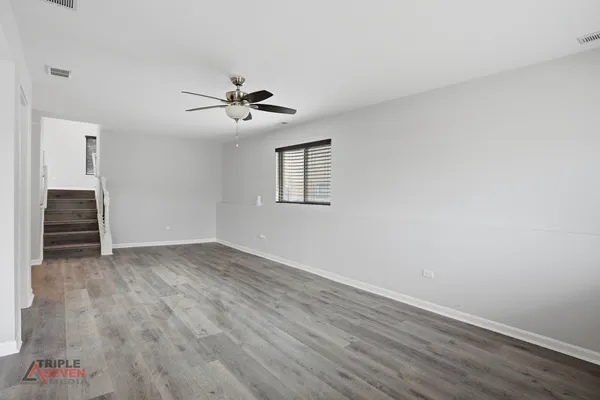 a view of empty room with wooden floor and ceiling fan
