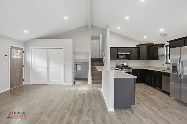 a large kitchen with a center island wooden floor stainless steel appliances and cabinets