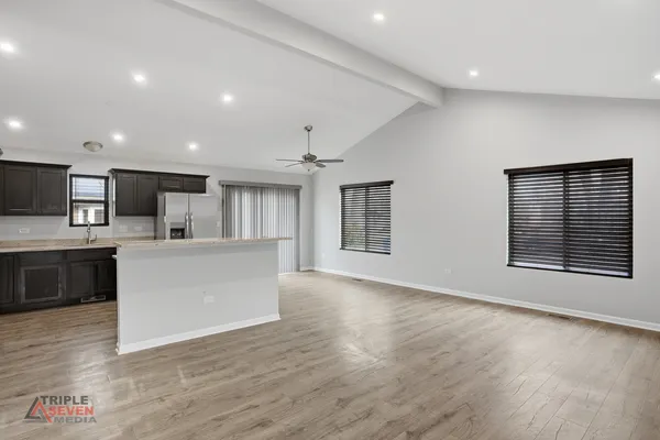 a view of an empty room with kitchen and window