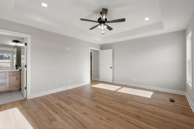 a view of an empty room with wooden floor and a ceiling fan