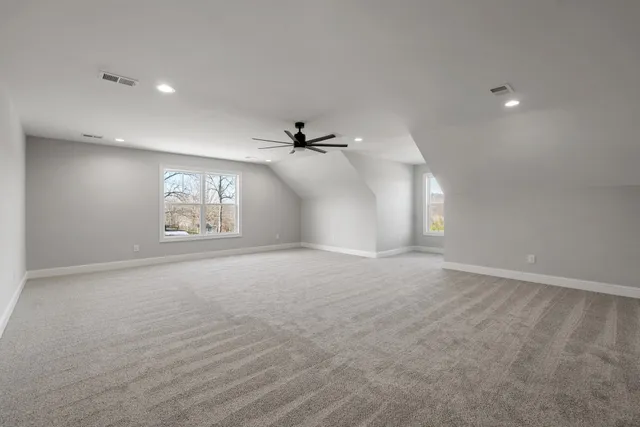 an empty room with windows and ceiling fan