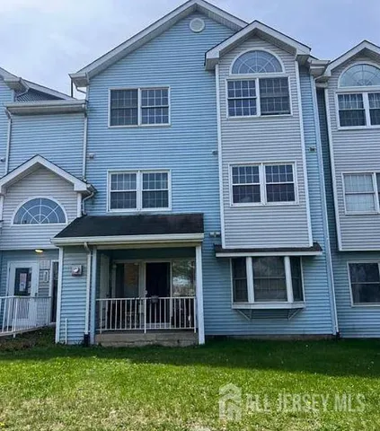 a view of a brick house with a yard plants and large tree