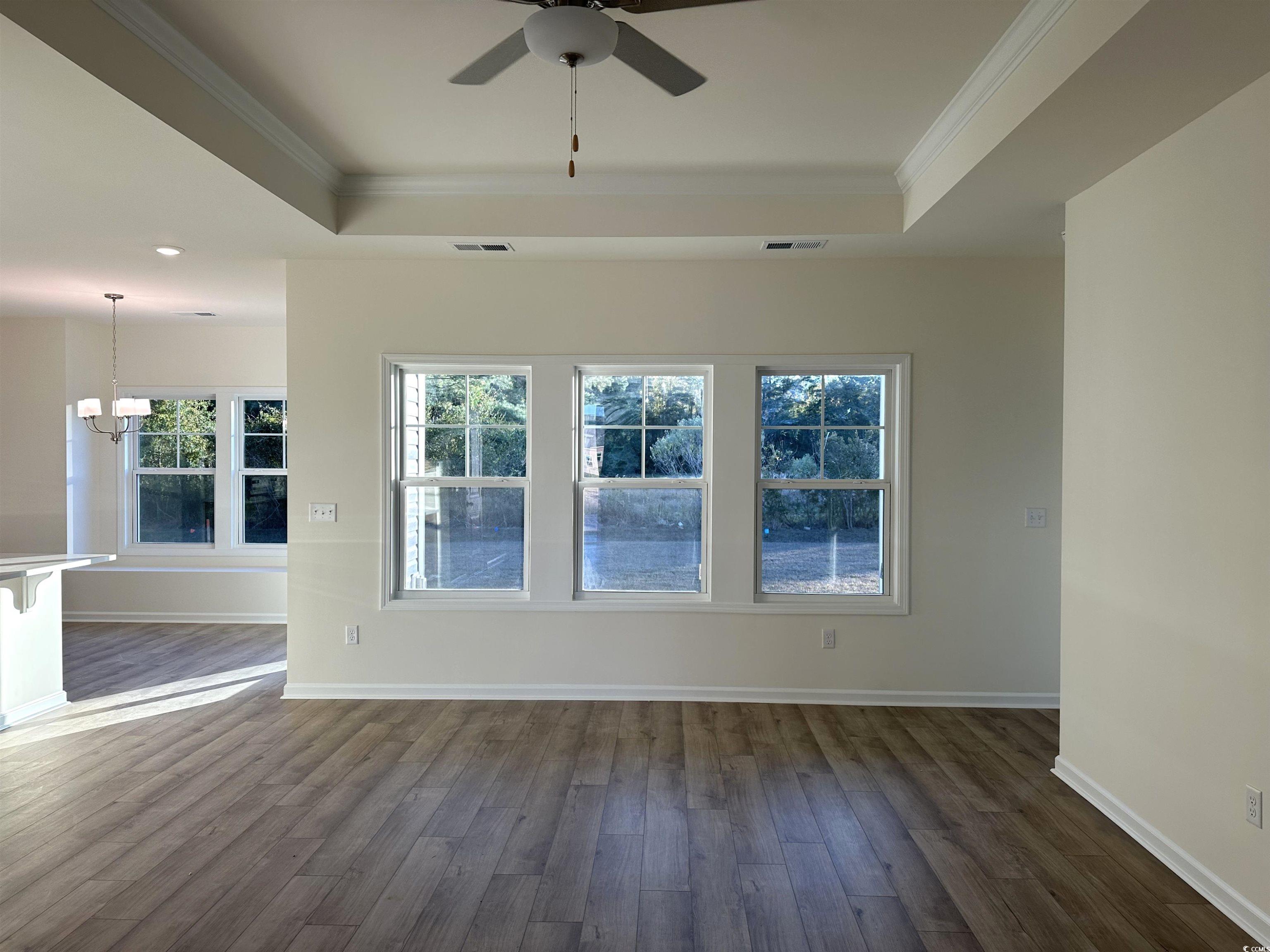 892 Birch Gdn Drive Longs, SC 29568 - Photo 2 of 15 Unfurnished room featuring a raised ceiling, wood finished floors, crown molding, and a chandelier