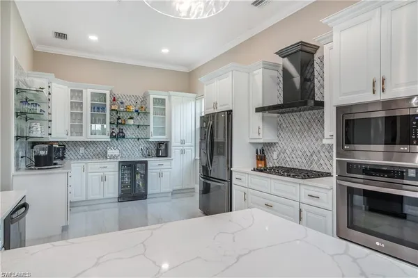 a kitchen with stainless steel appliances kitchen island granite countertop a refrigerator oven a sink dishwasher and white cabinets next to a window