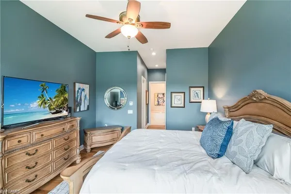 a bedroom with a large bed and a flat tv screen on dresser