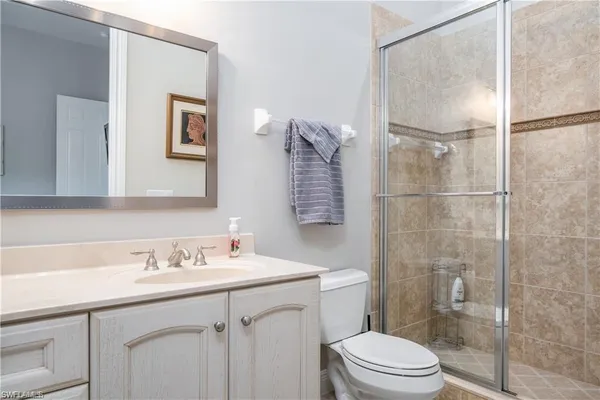 a bathroom with a granite countertop sink toilet and mirror