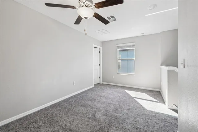 an empty room with a ceiling fan and window