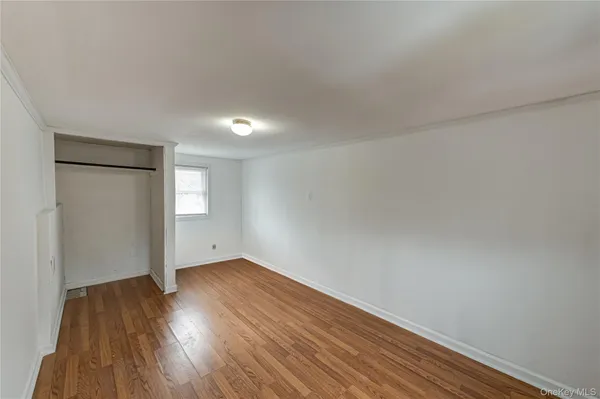 a view of an empty room with wooden floor and closet