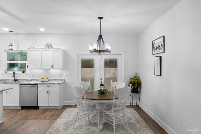 a kitchen with stainless steel appliances a dining table chairs and white cabinets