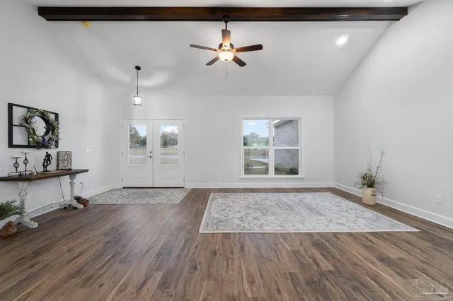 a view of an empty room with a window and wooden floor