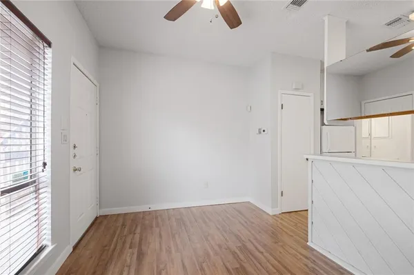 a view of an empty room with wooden floor and window