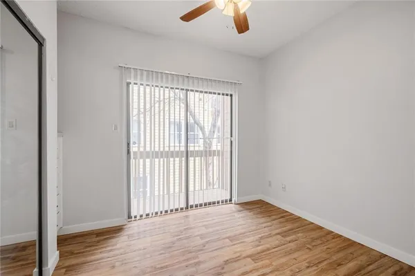 an empty room with wooden floor chandelier fan and windows