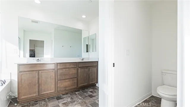a spacious bathroom with a toilet a sink and a mirror
