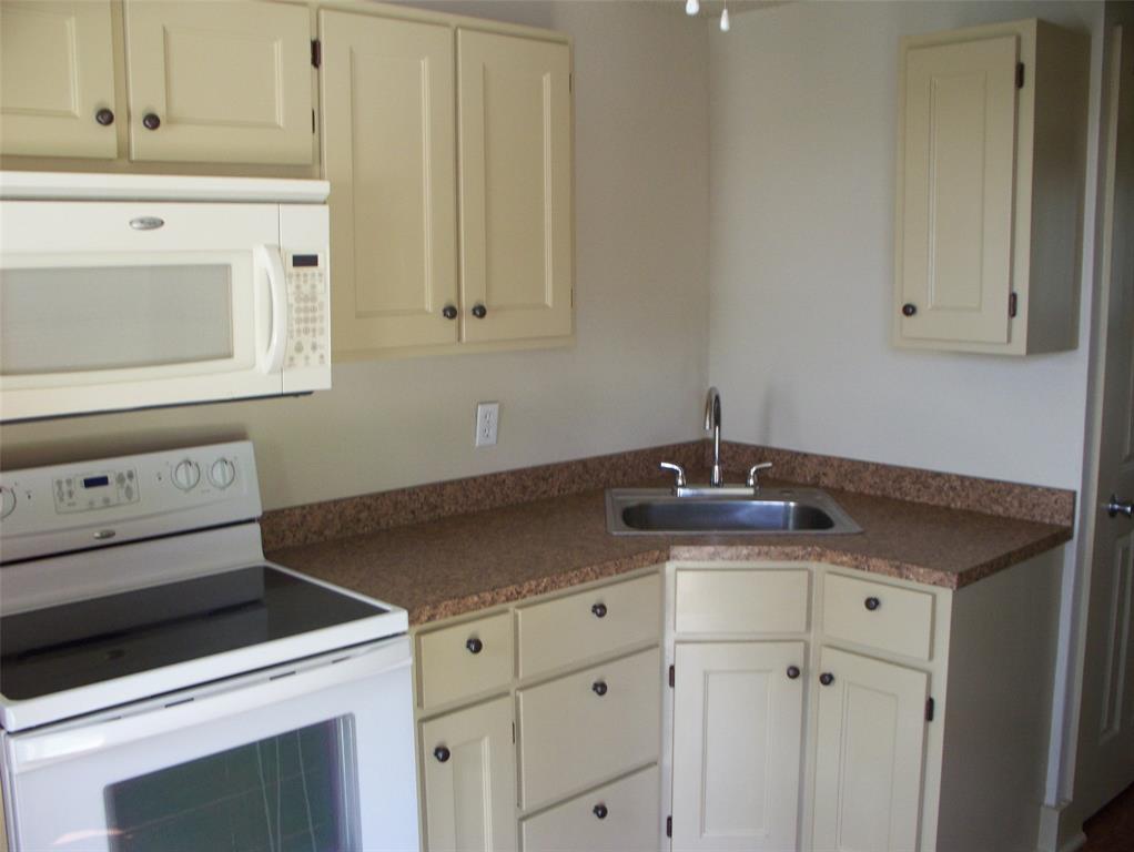 705 South Street, Unit A Graham, TX 76450 - Photo 4 of 7 a kitchen with granite countertop white cabinets and white appliances