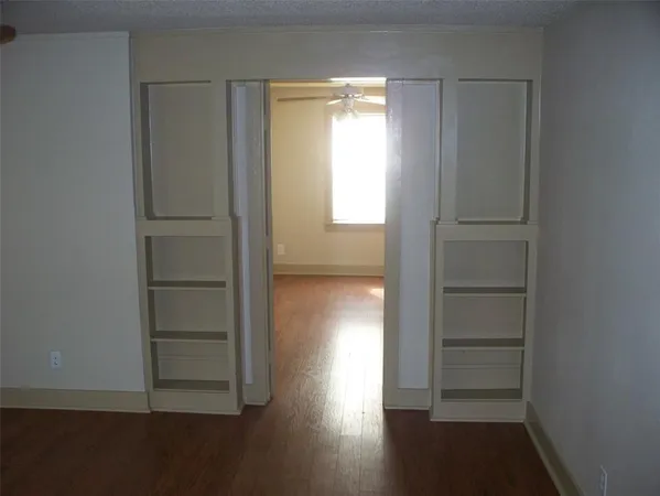 an empty room with wooden floor closet and windows