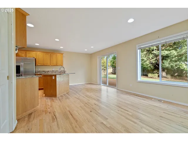 a kitchen with stainless steel appliances granite countertop a refrigerator a sink dishwasher and a oven with wooden floor