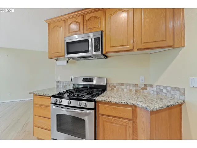 a kitchen with stainless steel appliances granite countertop a sink stove and microwave