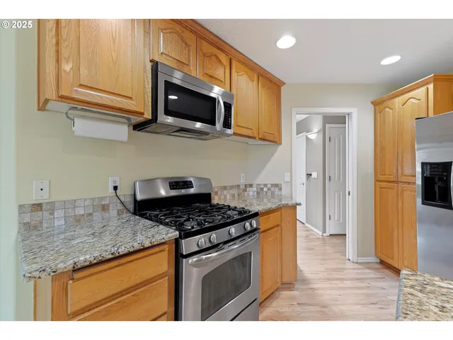 a kitchen with stainless steel appliances granite countertop a stove a sink and a microwave