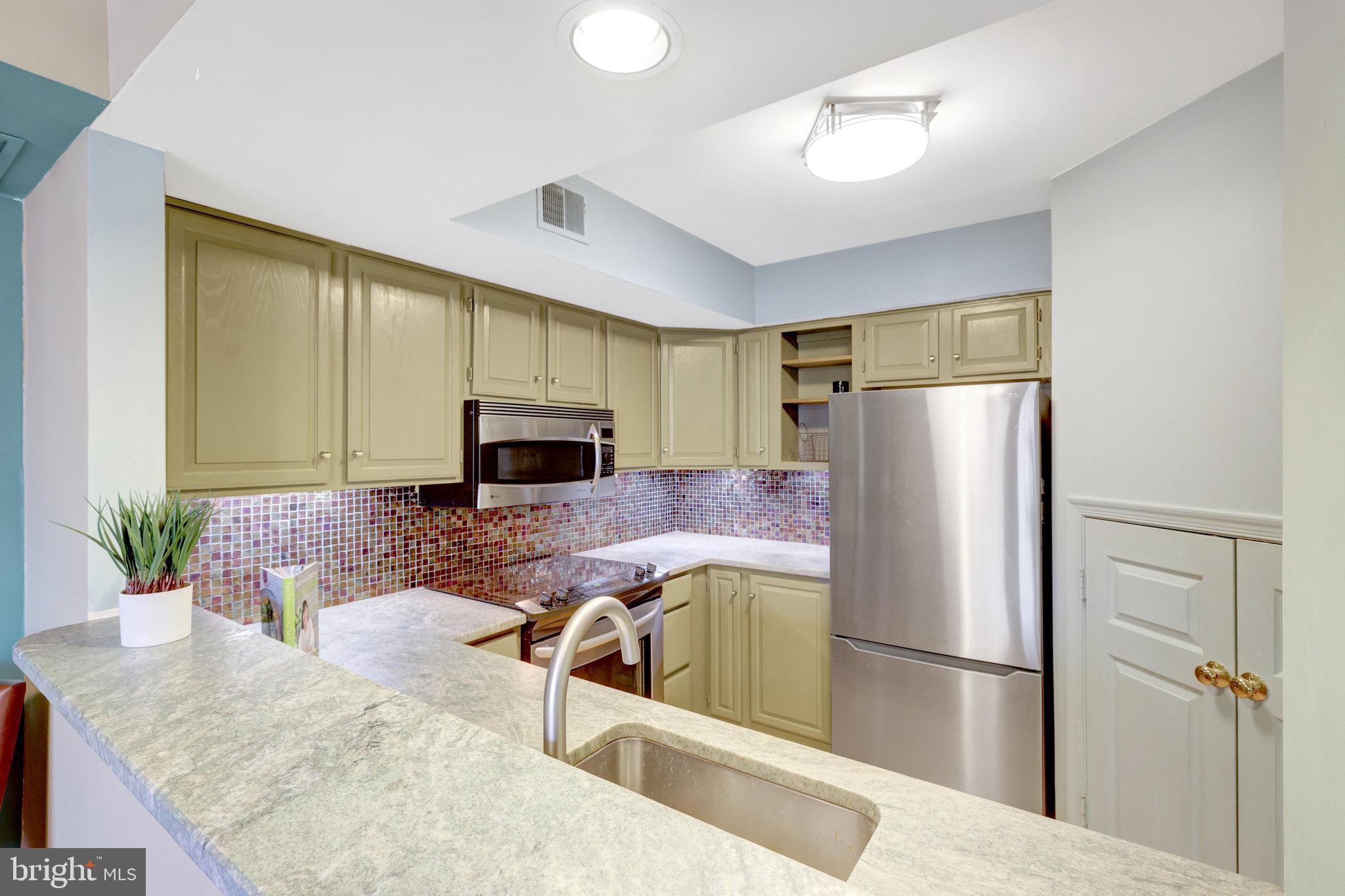 1334 Garden Wall Circle, Unit E Reston, VA 20194 - Photo 6 of 23 a kitchen with stainless steel appliances granite countertop a refrigerator a stove and a sink with wooden floor