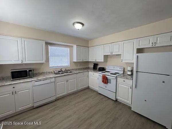 a kitchen with granite countertop white cabinets and white appliances