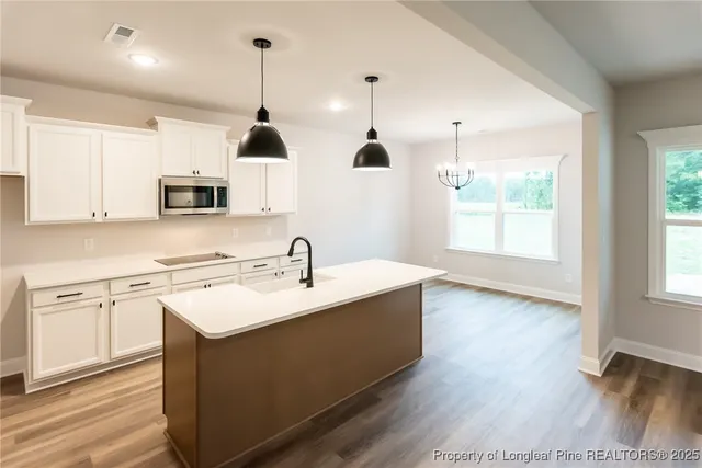 a kitchen with stainless steel appliances granite countertop a sink a stove and a wooden floors