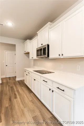 a kitchen with granite countertop white cabinets and stainless steel appliances