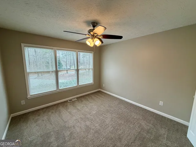 an empty room with windows and fan