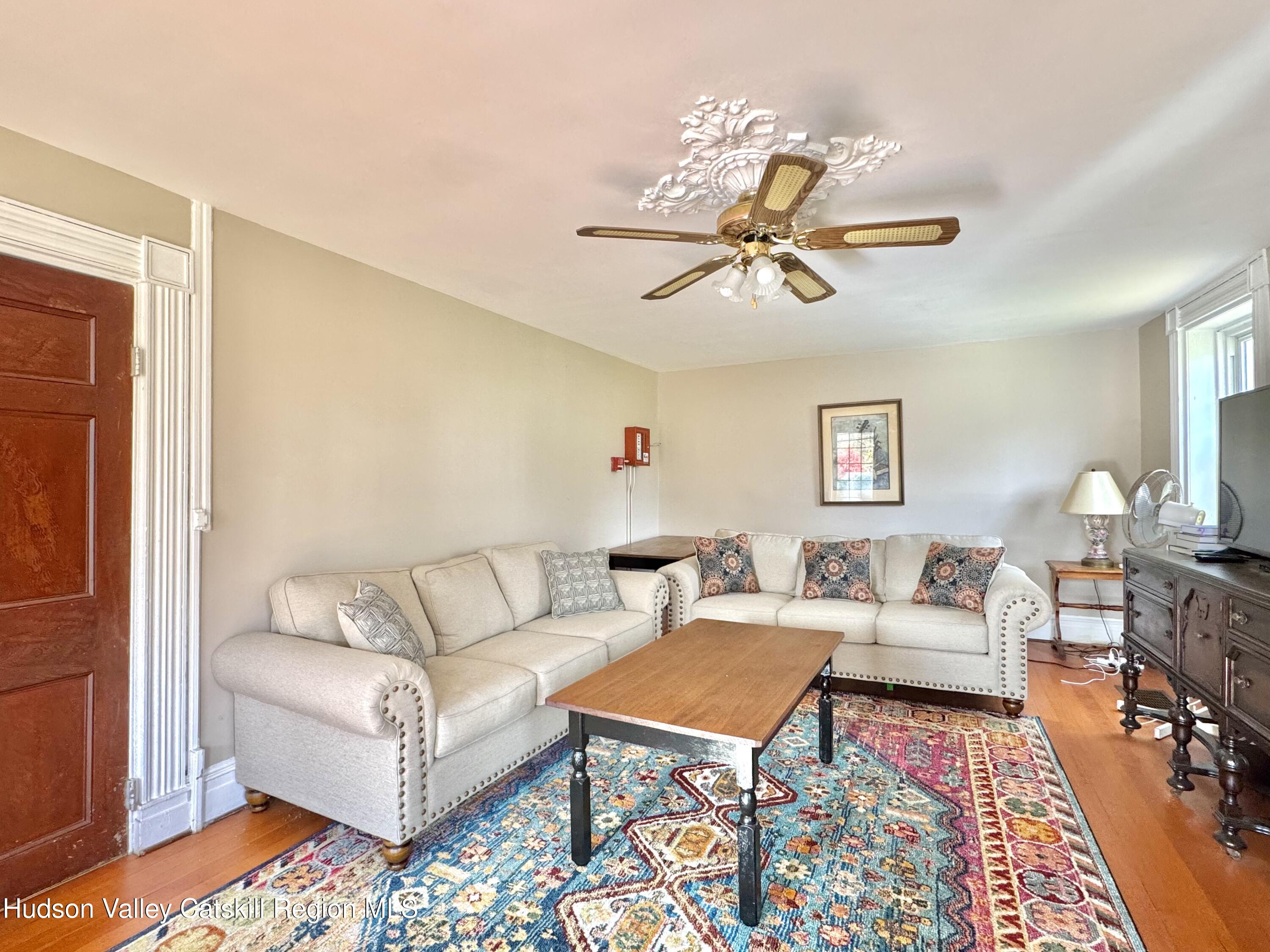 1114 Main Street Catskill, NY 12451 - Photo 13 of 40 a living room with furniture a rug and a chandelier