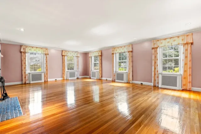 a view of an empty room with window and wooden floor