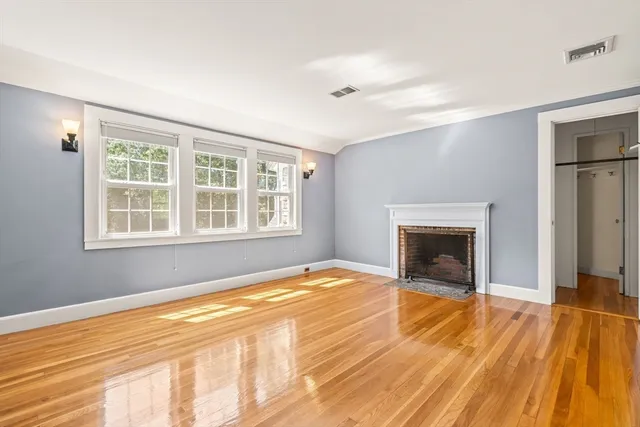 a view of empty room with wooden floor and fireplace