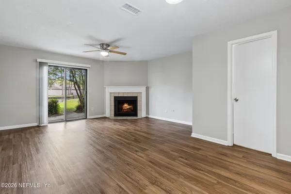 an empty room with wooden floor fireplace and windows