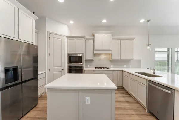 a kitchen with stainless steel appliances a sink stove refrigerator and cabinets