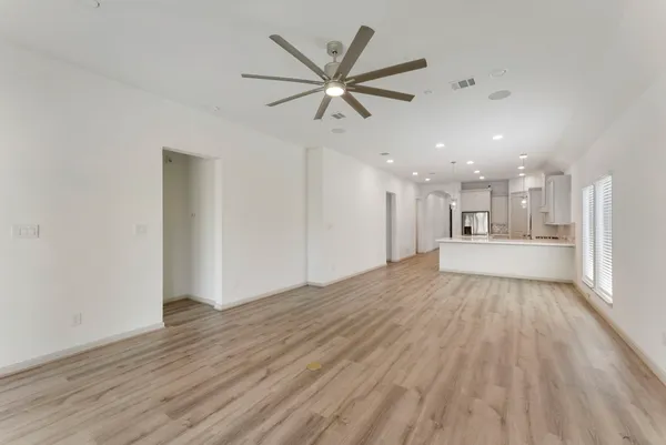 a view of an empty room with wooden floor and a ceiling fan