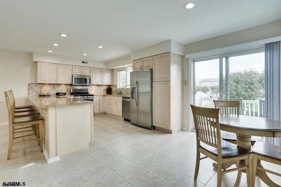 433 Albacore Lane Brigantine, NJ 08203 - Photo 13 of 22 a kitchen with a table chairs refrigerator and microwave