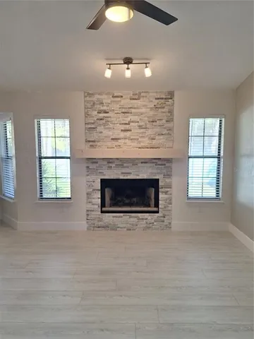 an empty room with windows fireplace and sink