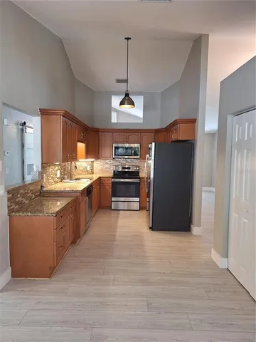 a large kitchen with stainless steel appliances granite countertop a stove and a refrigerator