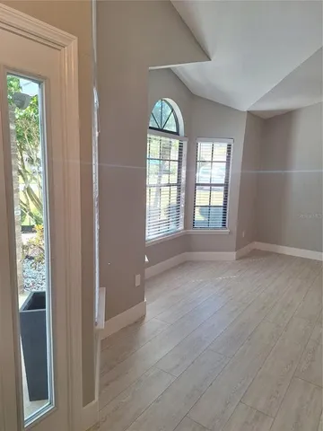 a view of an empty room with wooden floor and a window