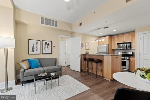 a living room with stainless steel appliances kitchen island granite countertop furniture and wooden floor