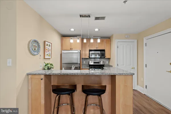 a kitchen with stainless steel appliances kitchen island granite countertop a stove a sink and a refrigerator
