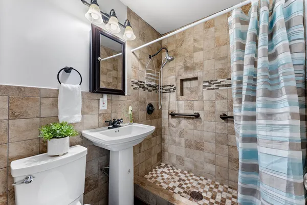 a bathroom with a sink a toilet and shower