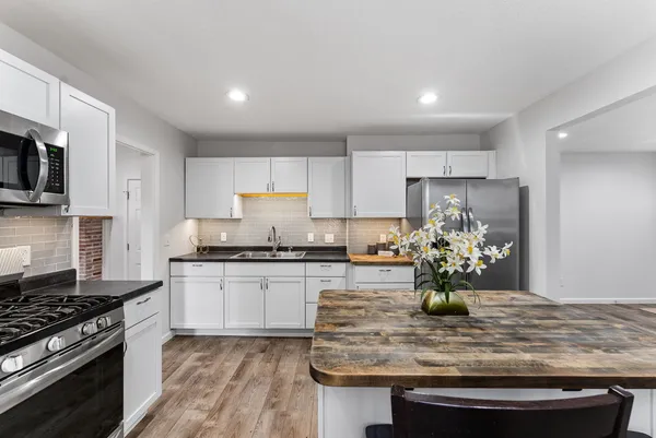 a kitchen with kitchen island granite countertop stainless steel appliances a sink a stove top oven a counter space and cabinets