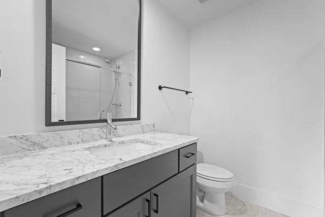 a bathroom with a granite countertop sink a toilet and a mirror