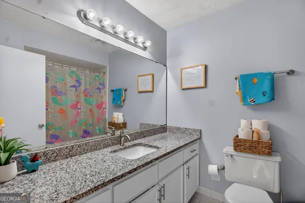 a bathroom with a granite countertop sink a toilet and mirror
